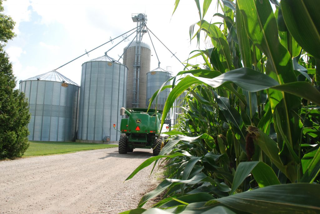 combine parked beside corn field and grain elevator