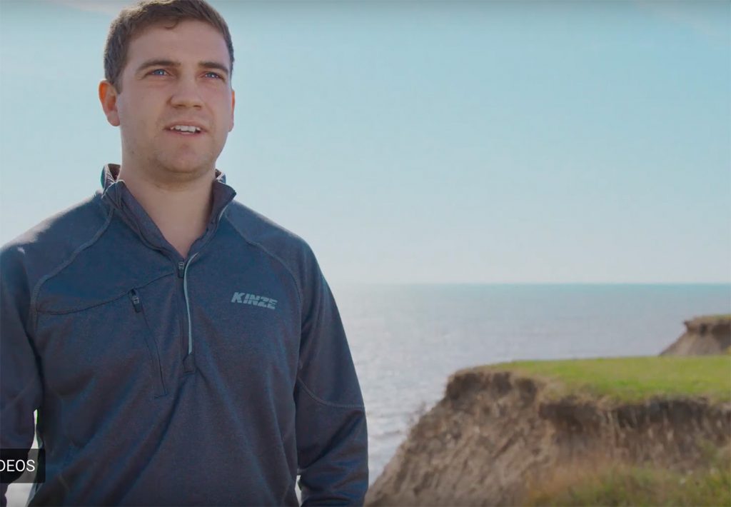 farmer Justin Bell standing in front of a shoreline overlooking water