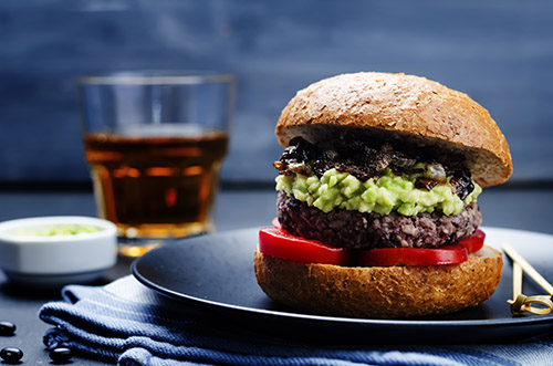 black bean burger with mashed avocado, caramelized onions and tomatoes. toning. selective focus