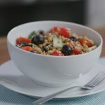 A bowl of wheat berry and lentil salad, sitting on a table.