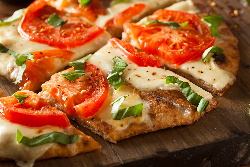 a thin-crust pizza with tomatoes and basil