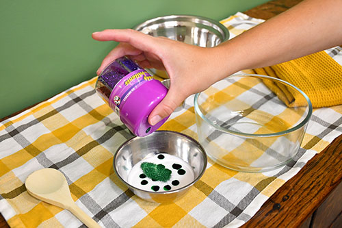 Making the corn slime. Adding green food colouring and glitter to the school safe glue