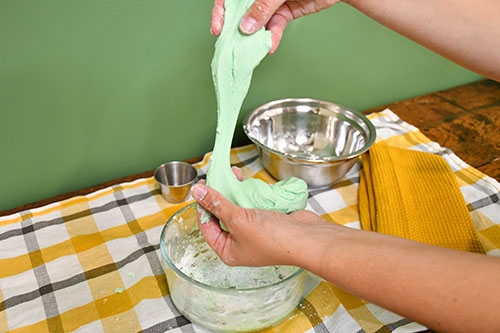 Stretching corn based slime on a yellow and white plaid background