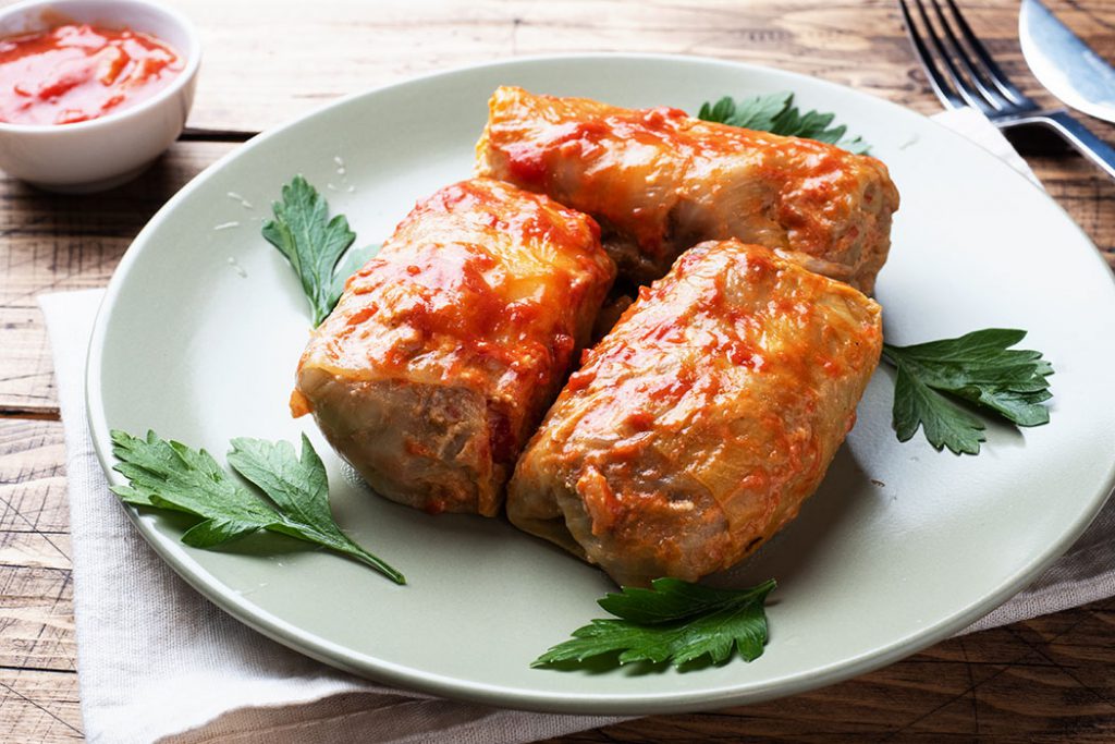 Cabbage rolls with pork, barley and vegetables on the plate. Stuffed cabbage leaves with meat. Wooden background