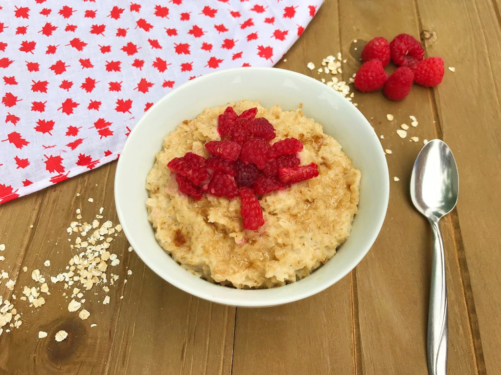 A bowl of homemade brown sugar and maple syrup oatmeal topped with raspberries to celebrate Canada Day 2020.