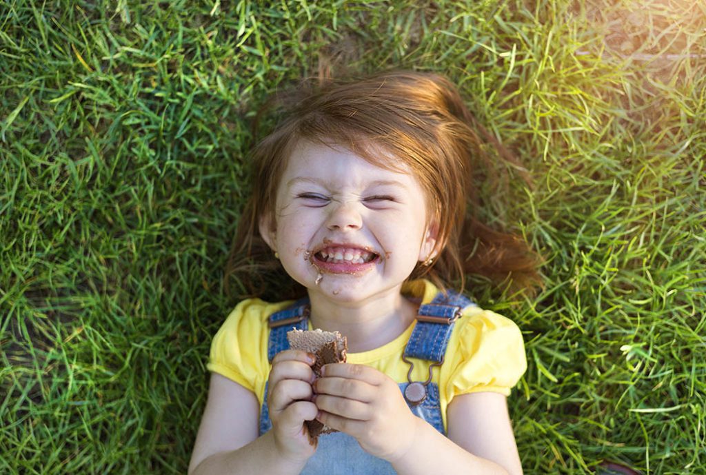 little girl eating wheat crackers in grass