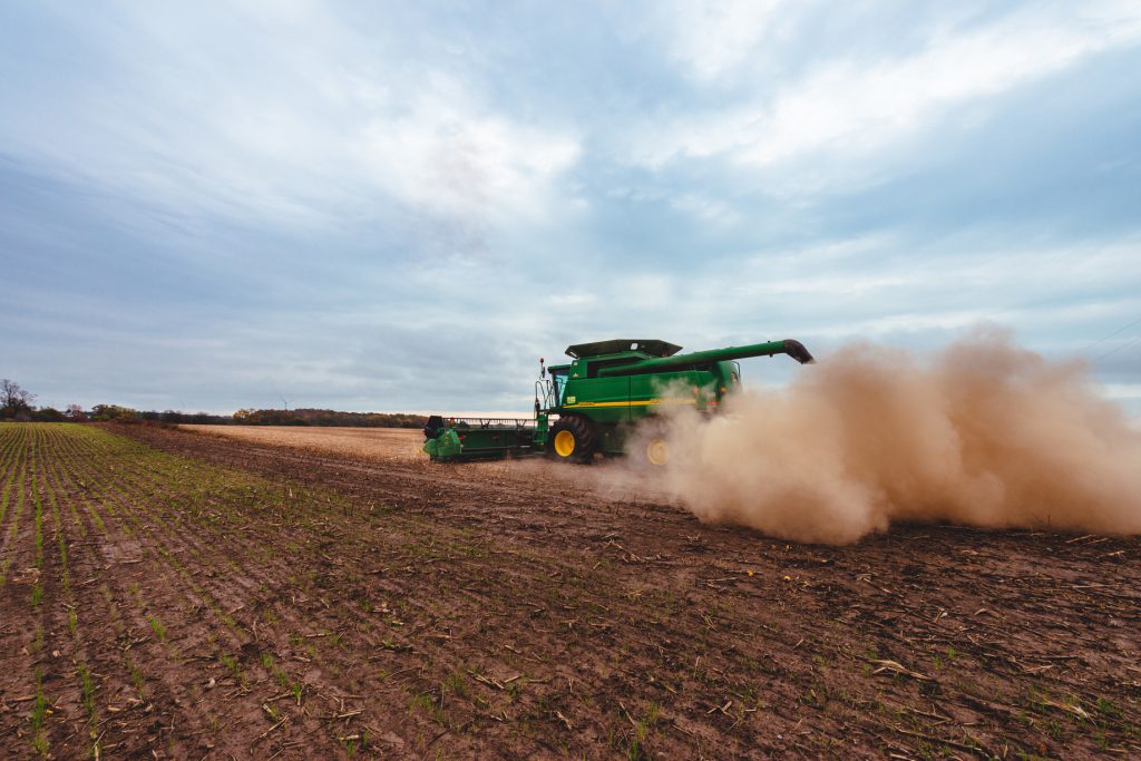 combine harvesting soybeans with lots of dust