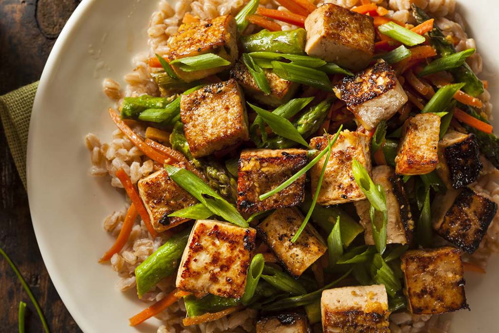 Sriracha flavoured tofu on a plate of coconut rice, asparagus and carrots. 