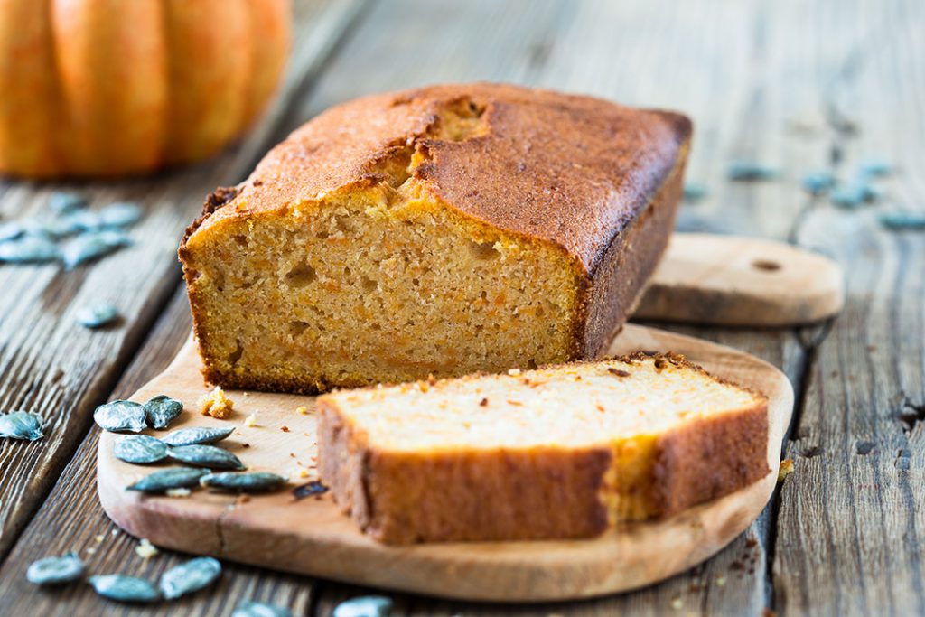 Homemade pumpkin bread baked in a loaf pan on a wooden board