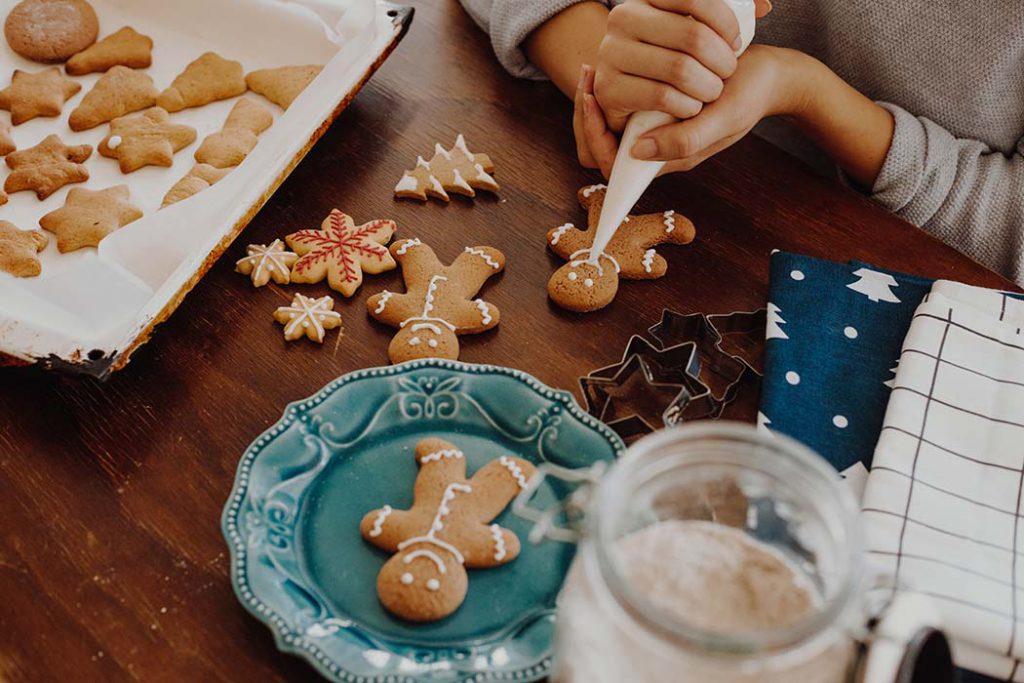 women decorating homemdae gingerbread Christmas cookies.