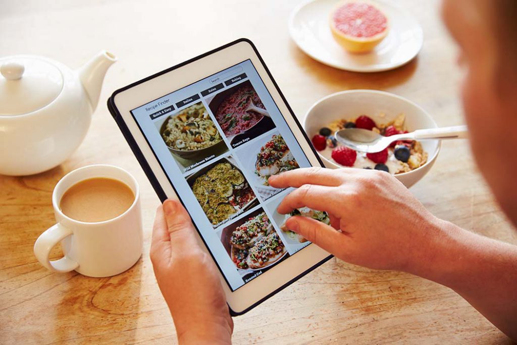 person looking at meal prep ideas while eating breakfast of oatmeal.