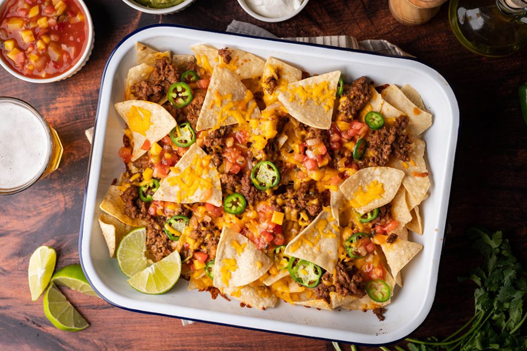 corn chip nachos with colourful toppings in a white sheet pan. 