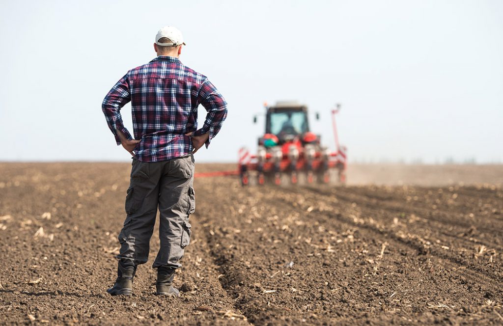 young farmer on farmland with tractor in background