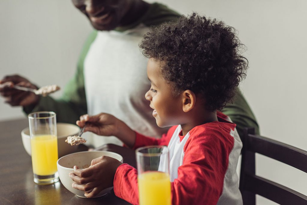 close-up shot of african-american father and son eating breakfast