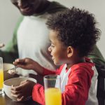 close-up shot of african-american father and son eating breakfast